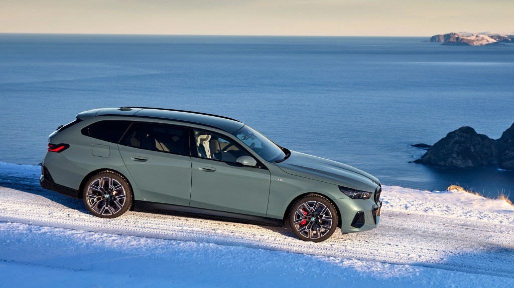 Side elevation of a green BMW i5 Touring on snow
