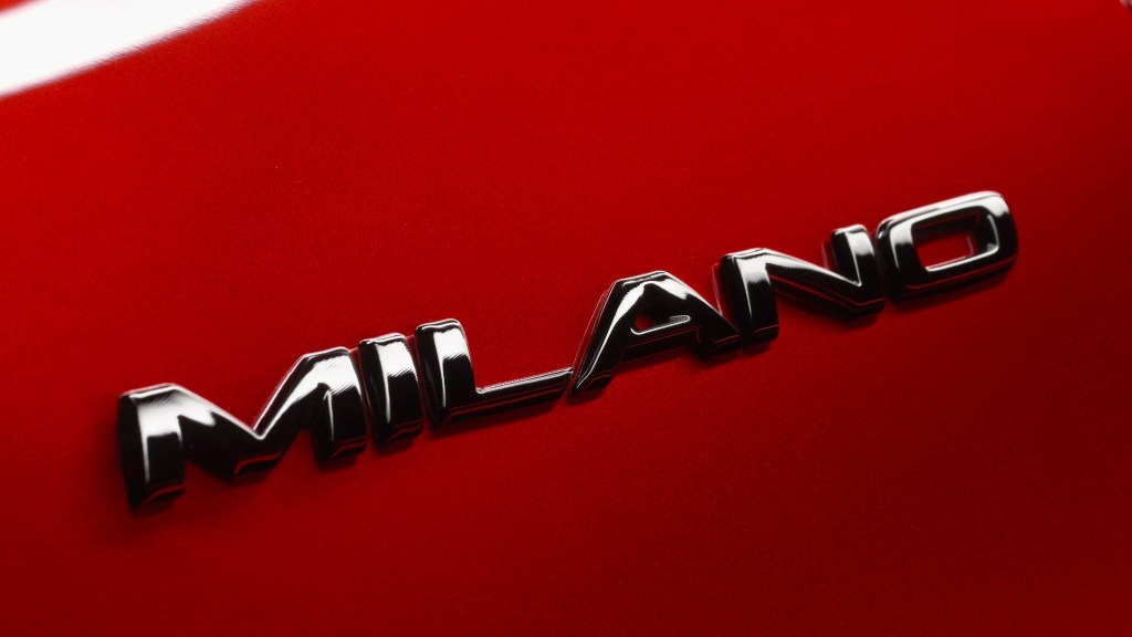 Detail of a Milano badge on a red Alfa Romeo Junior